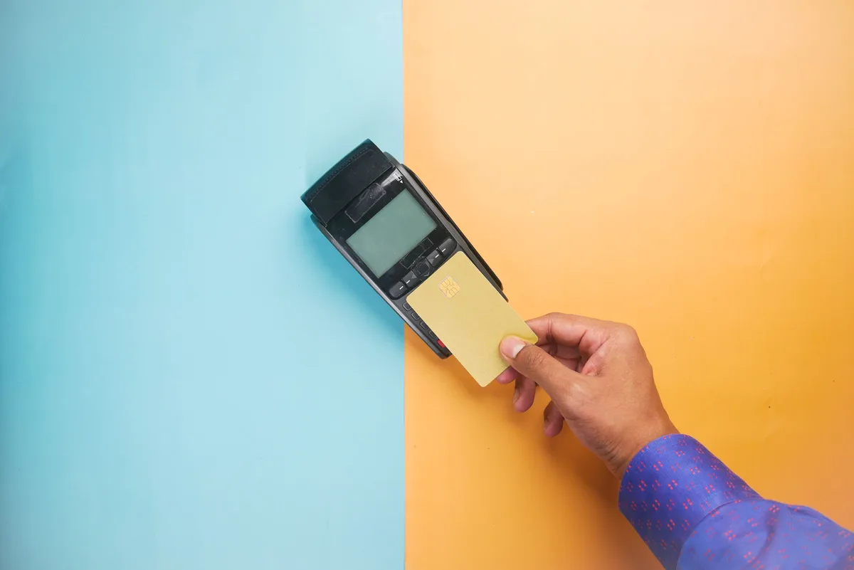 A hand tapping a card on a contactless payment terminal, the transaction layer agentic AI companies are now building rails for