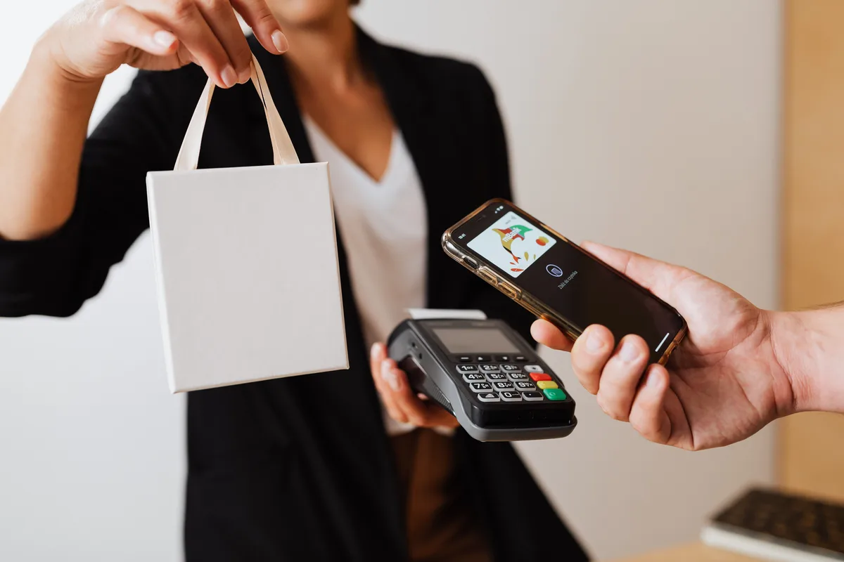 A shopper paying by phone at a card terminal, the checkout step agentic AI use cases in commerce aim to automate