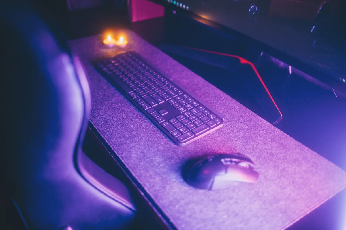 A keyboard and mouse lit on a dark desk, the interface an AI agent drives when it controls mouse and keyboard input