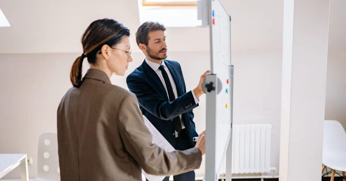 Two colleagues planning on an office whiteboard, scoping an AI agent development services engagement