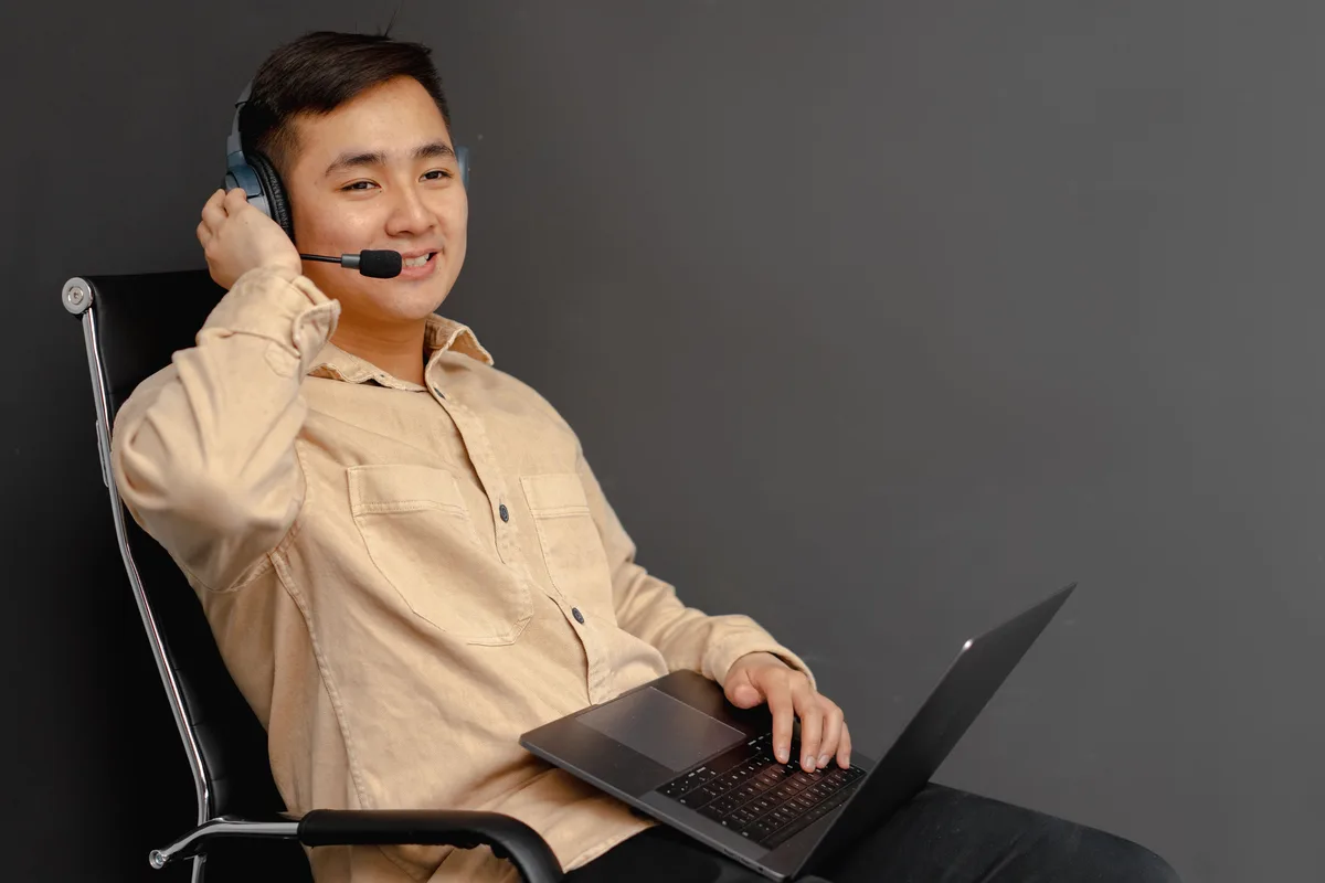 A customer support worker in a headset working at a laptop, the kind of role an AI voice agent supports for businesses
