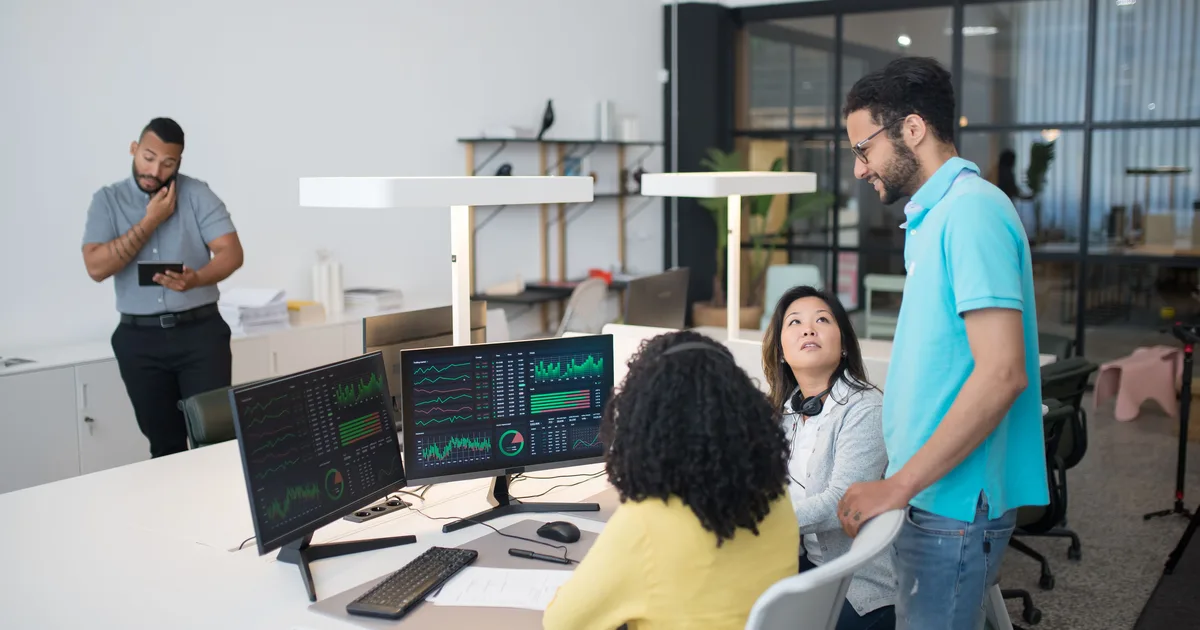 A business team collaborating around laptops in a modern office, the setting where teams decide which AI agents to build
