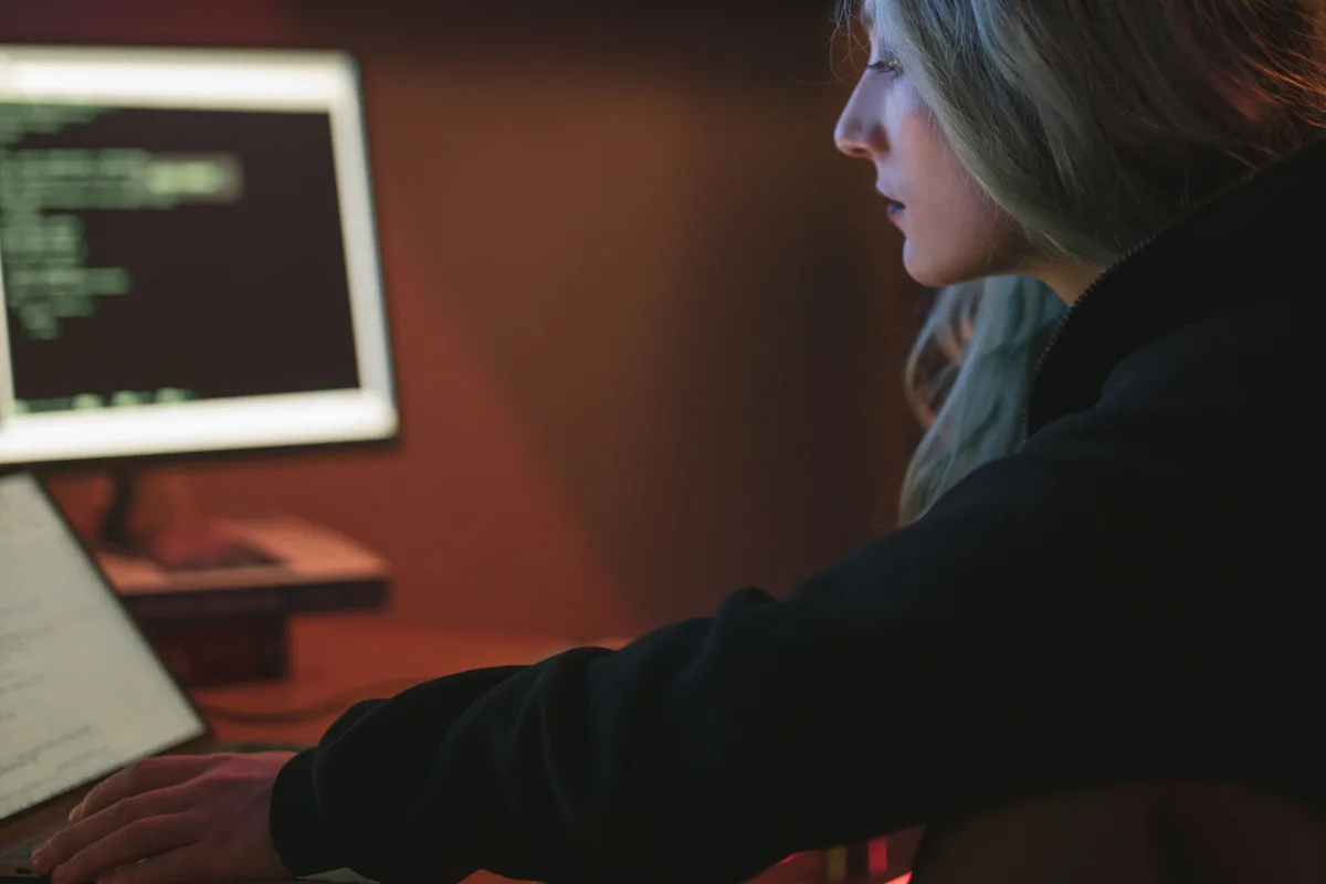 A developer working late at a laptop beside a monitor full of code, the kind of evening when a first AI API integration comes together