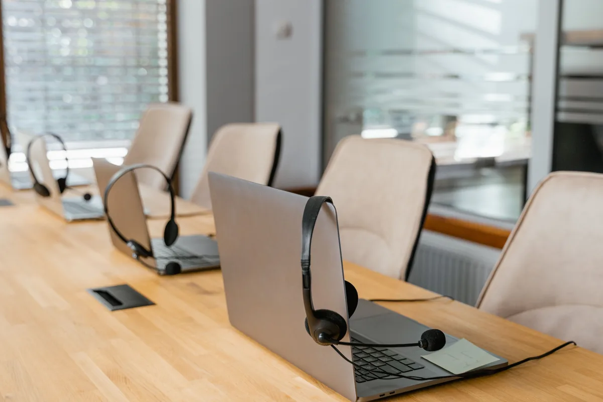 A row of laptops with headsets in an empty call center, the kind of support desk an AI call center voice agent works alongside