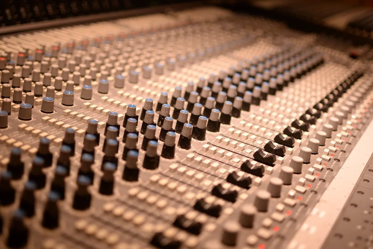 An analog audio mixing console with rows of knobs and sliders, a picture of how AI voice agents route audio through a chain of processors