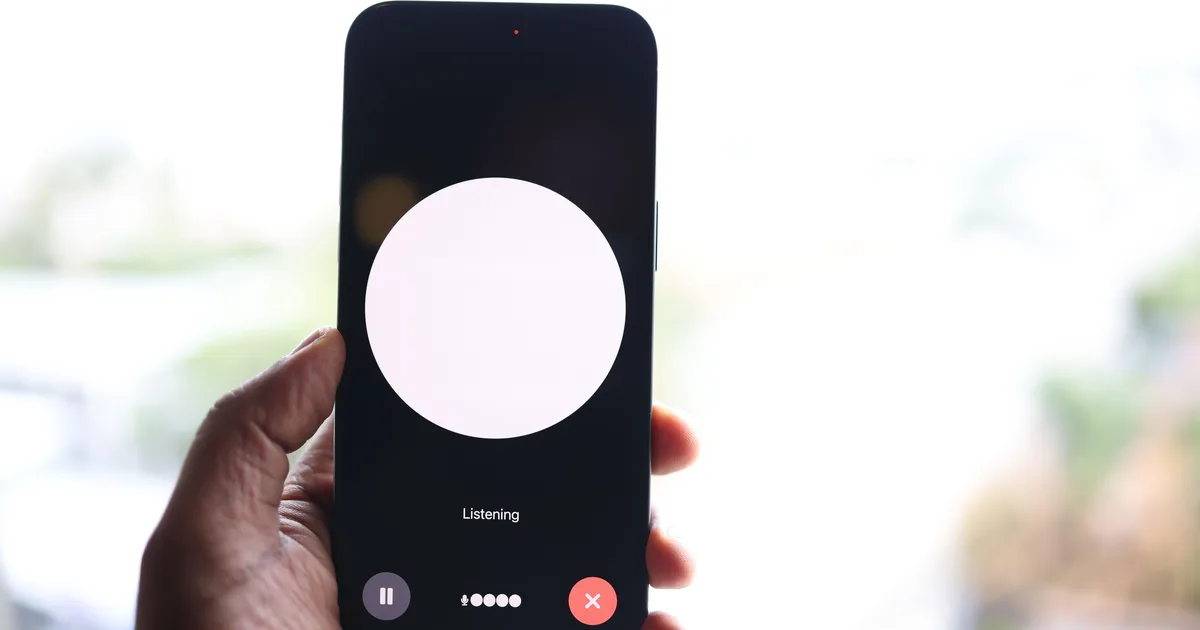 A hand holding a smartphone showing a voice assistant screen that reads Listening, the interface AI voice agents present to callers
