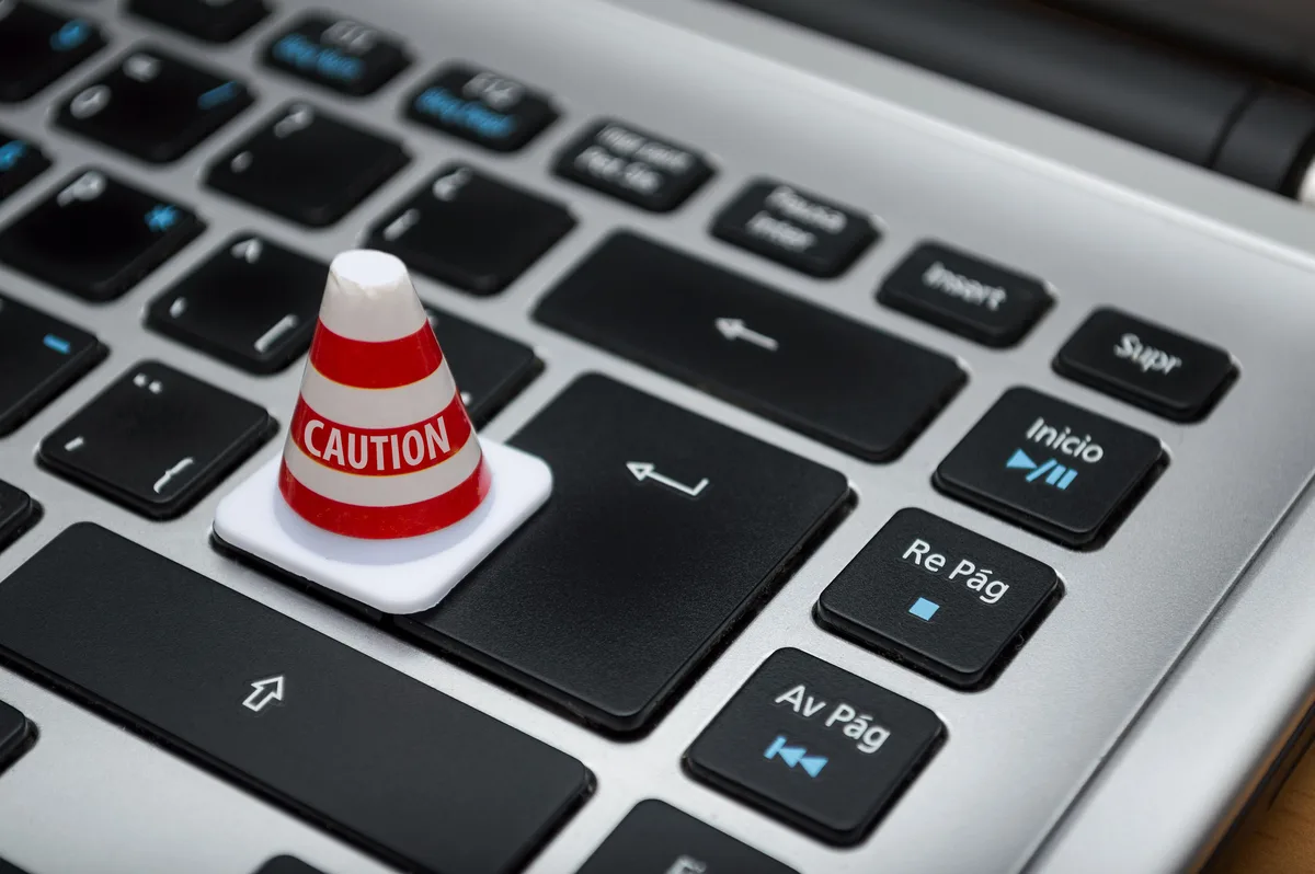 A miniature caution cone standing on a laptop keyboard, marking the generative AI security limits on a task