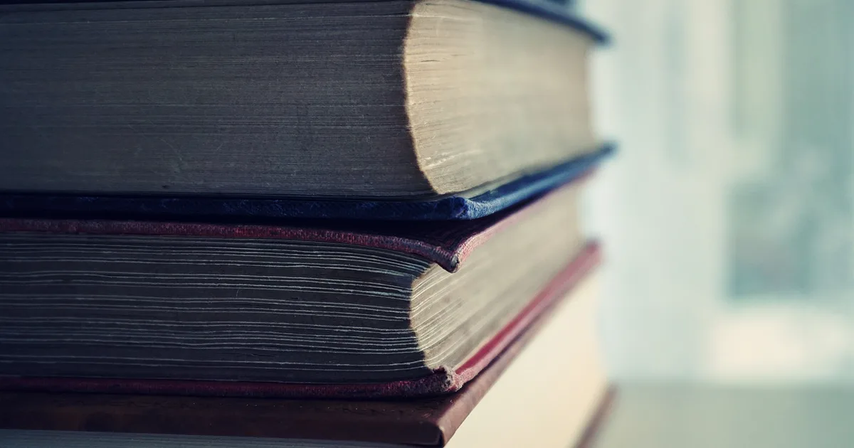 Close-up of stacked hardcover books with worn page edges, illustrating a ranking of the best books on LLMs in 2026