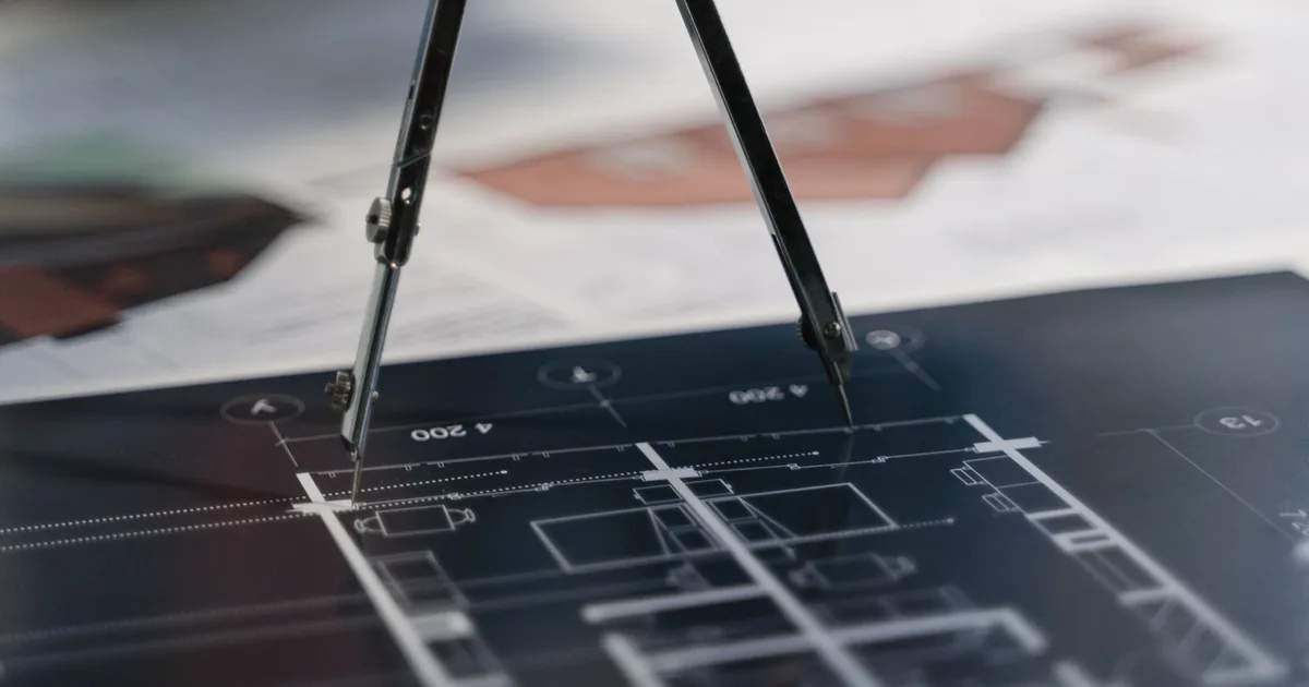 Drafting compass resting on architectural blueprints, the planning stage where problem-first agentic AI applications begin