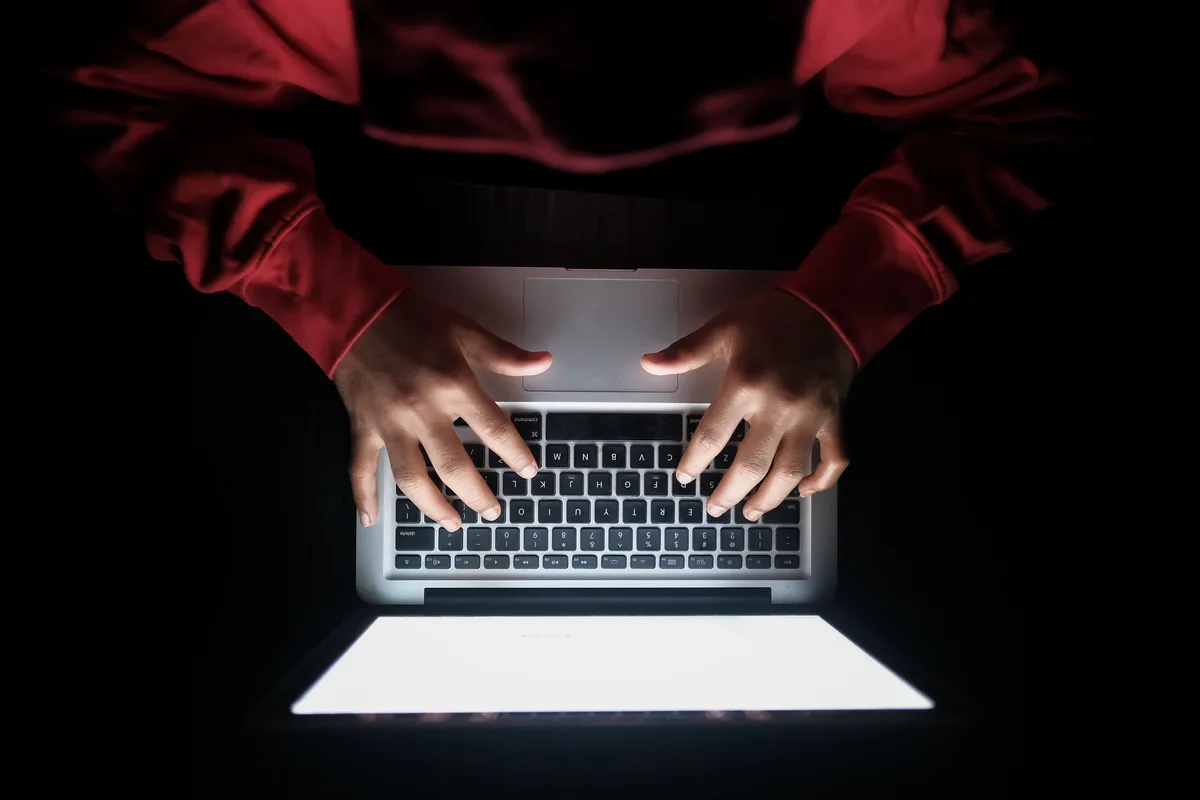 Top view of hands typing on a laptop with a bright screen in a dark room, the kind of Claude Code session that quietly consumes a plan's usage