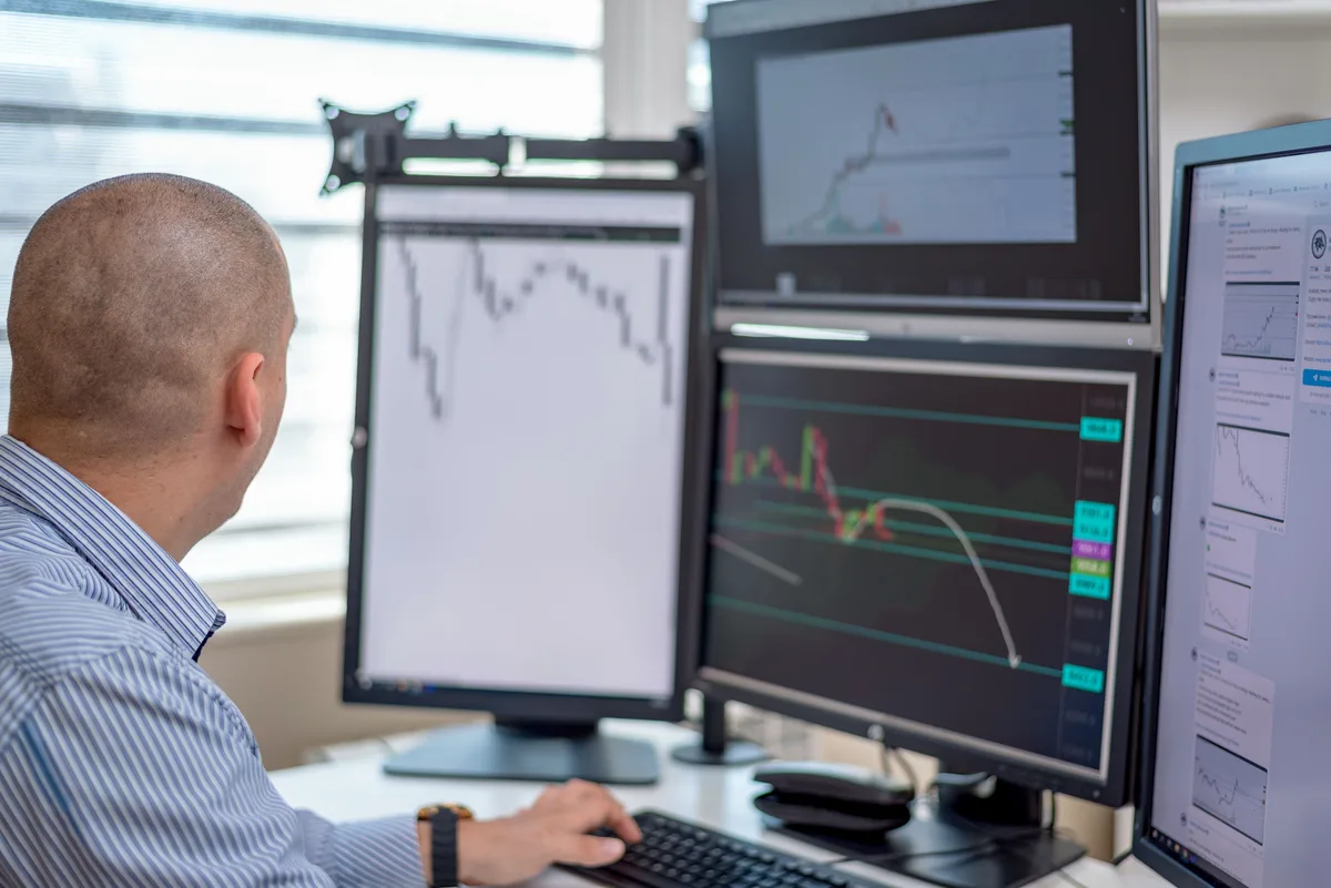 Trader reviewing price charts on several monitors, the kind of data a convolutional neural network for the stock market learns from
