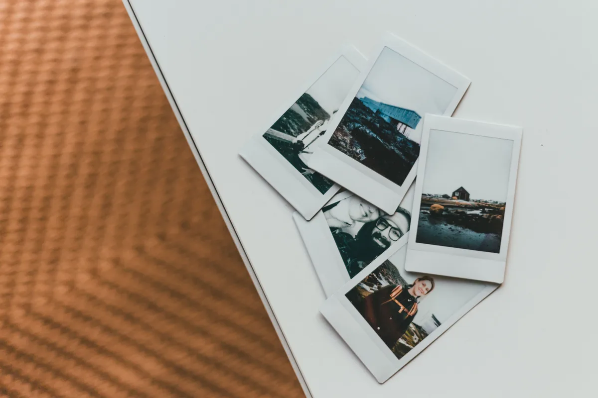 Polaroid photos arranged in a grid on a table, the filing habit an AI prompt library needs
