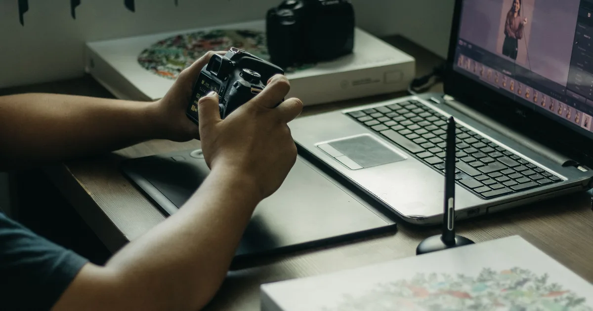 A photographer at a desk with a camera and a laptop, the starting point for creating an AI prompt from a photo