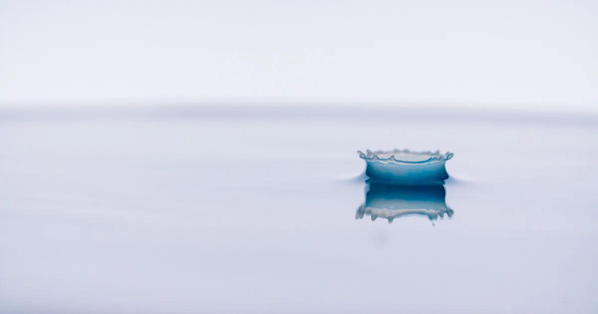 A water droplet forming a crown-shaped splash on a still surface, frozen the way Grok AI prompts for slow motion try to capture it