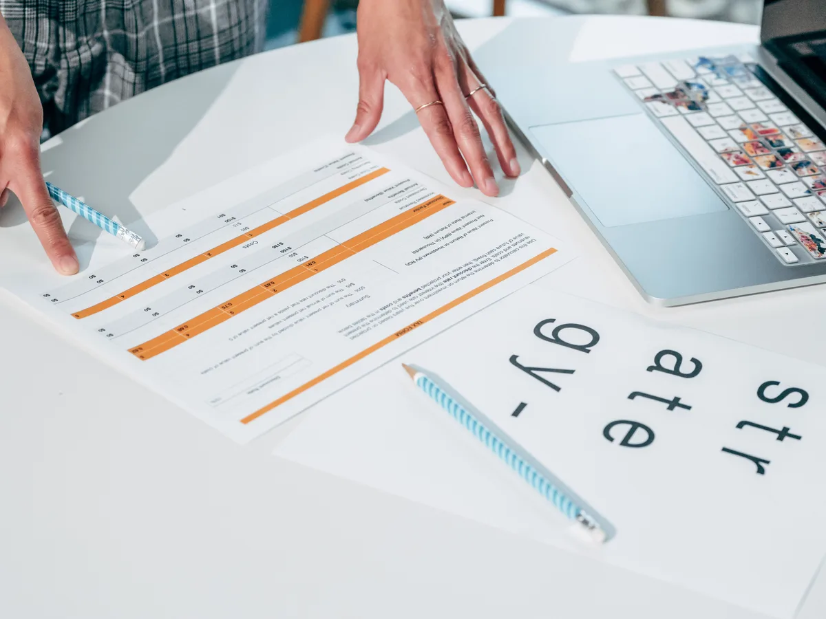 Hands reviewing printed documents and papers on a desk