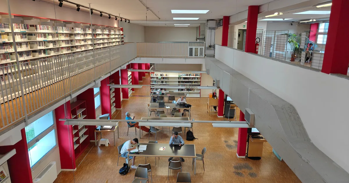 A bright library reading room seen from above, with researchers working at tables