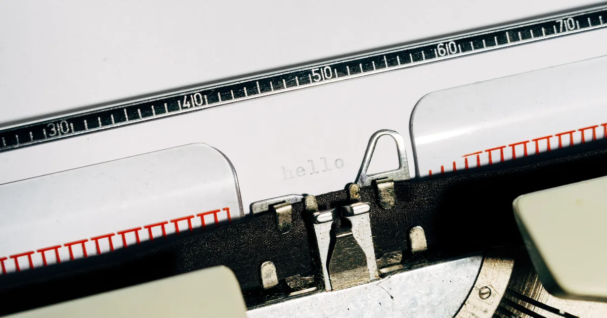 A vintage typewriter typing hello on white paper, a nod to prompting AI to write like a human