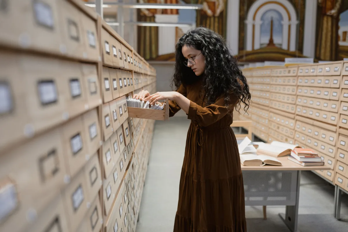 A researcher pulling a drawer from a library card catalogue, the retrieval step that decides brand visibility in AI search engines