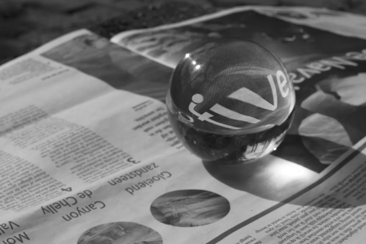 A glass sphere distorting the newspaper text beneath it, a picture of how a model can bend an accurate source while summarising it