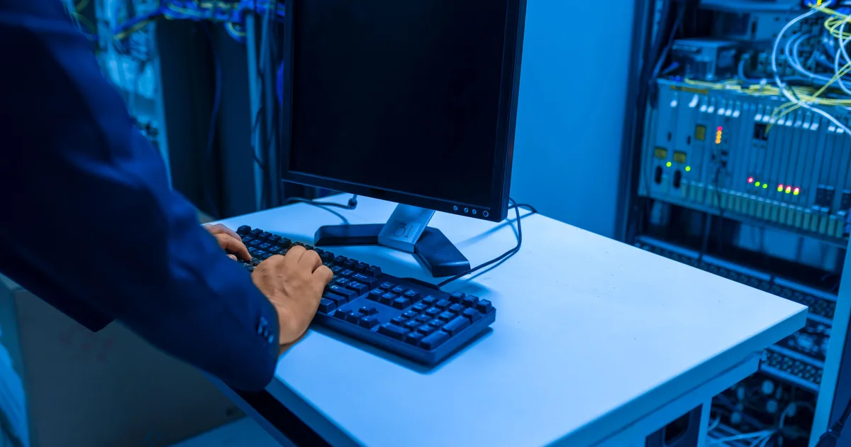 Engineer typing at a terminal in a server room, the operations side of running LLM apps that LLMOps covers