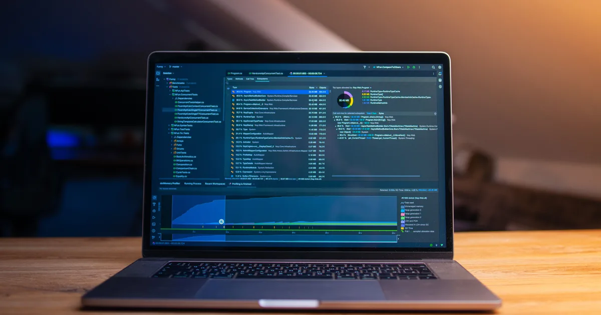 A laptop showing code on a wooden desk in a dim room, the kind of everyday machine that can run a local LLM