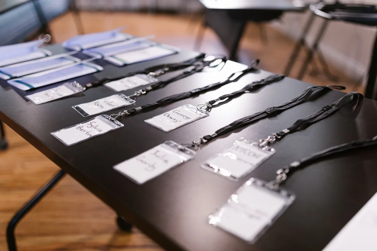 Rows of conference name badges on lanyards, each with a handwritten name, the kind of names a pattern rule has to recognise