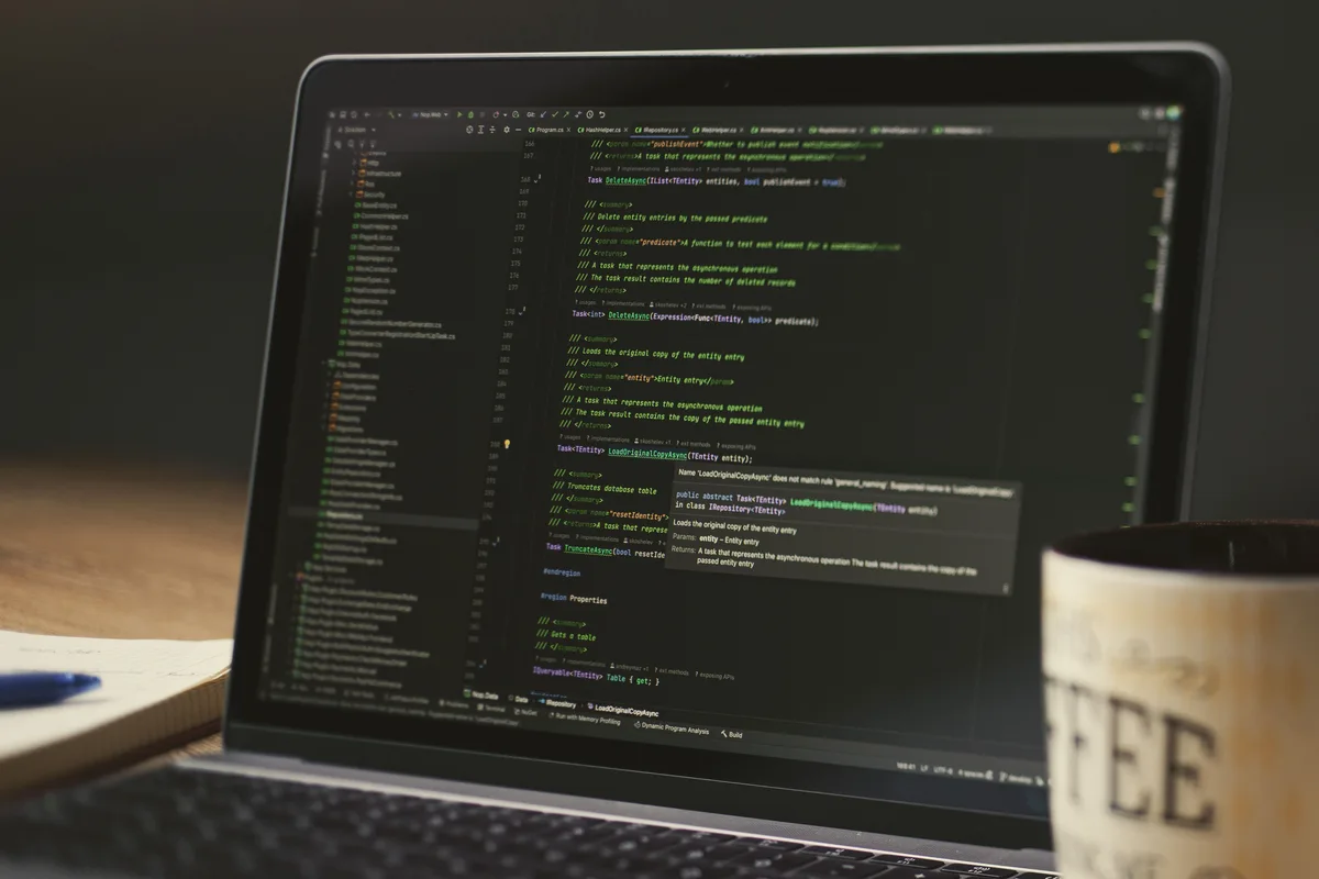 Laptop showing Python code in a dim room with a coffee mug, the setting for running a PyTorch neural network recipe