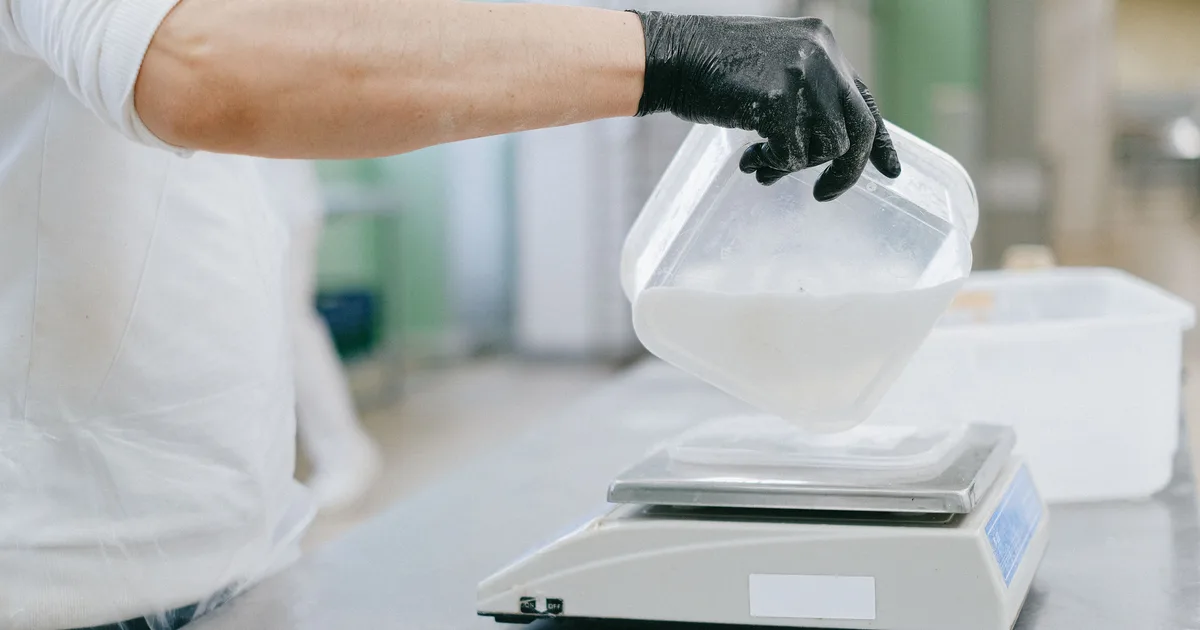 Cook weighing an ingredient on a digital kitchen scale, measuring each step the way a neural network recipe does
