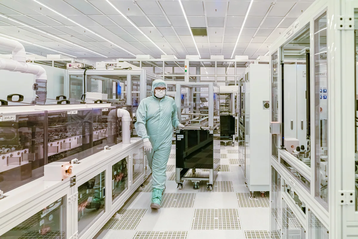 Technician in protective gear inside a cleanroom, where the chips behind every AI engine are fabricated
