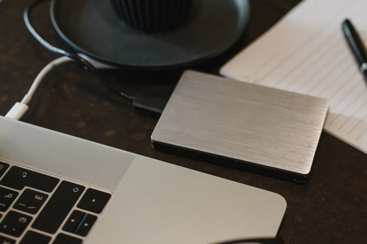 External hard drive connected to a laptop by USB cable, the kind of local copy that outlives a deleted Claude AI project