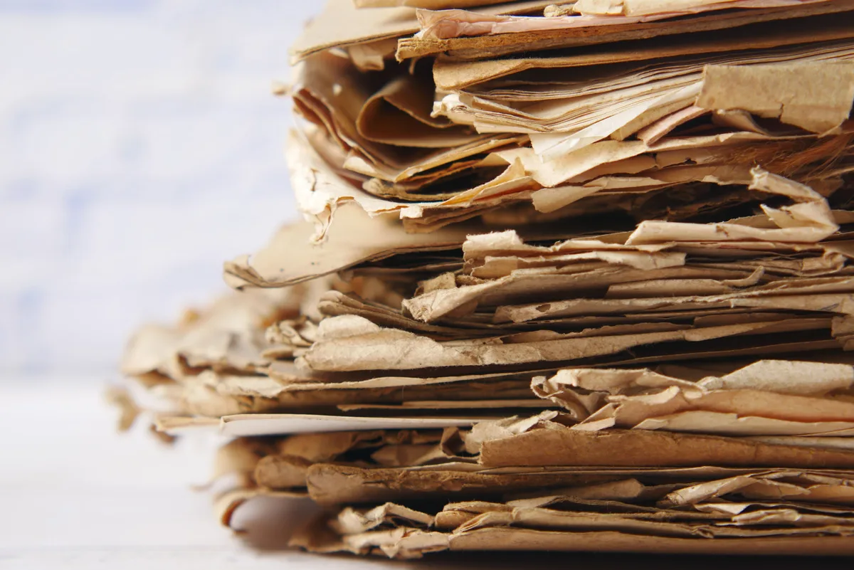 A thick stack of aged, crumpled paper documents, standing in for the records still held during Claude AI's 30-day deletion window
