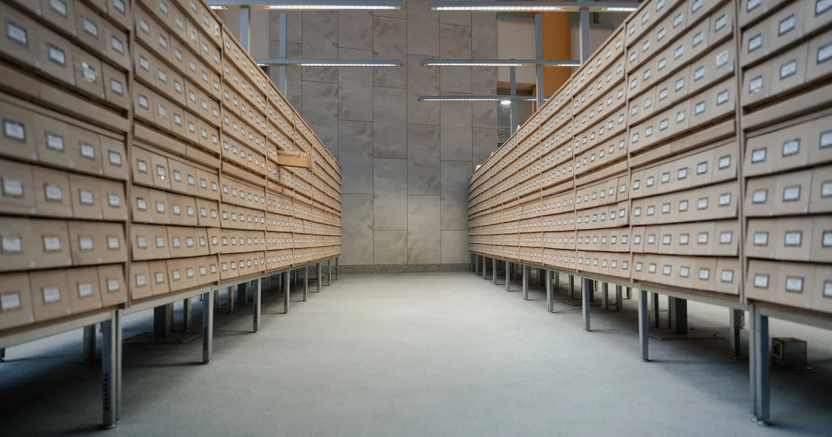 Rows of wooden drawers in a modern library archive, a physical stand-in for the archived projects on Claude AI that people mistake for deleted ones