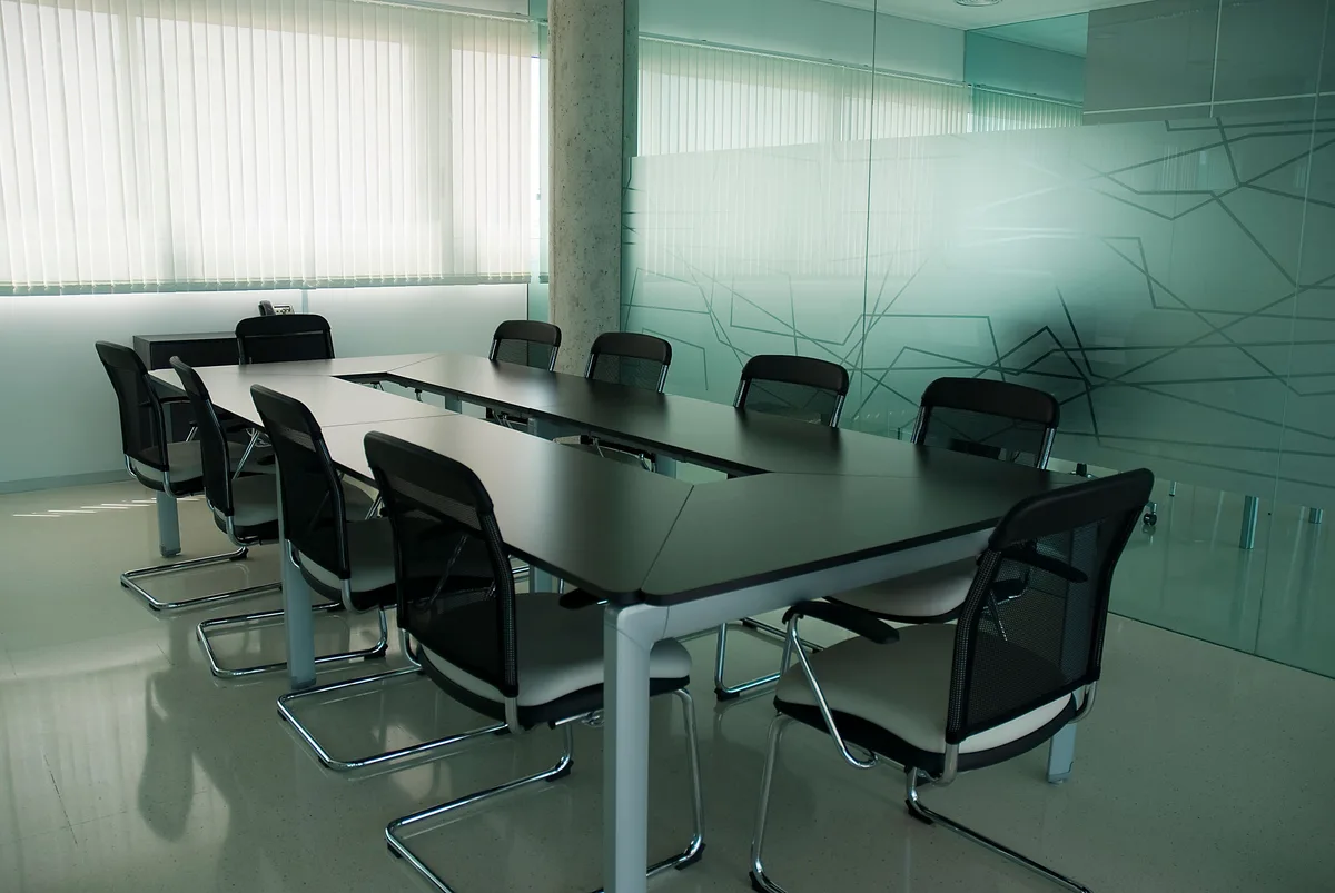 Empty boardroom with black chairs around a long table, where questions like who owns Claude AI get settled