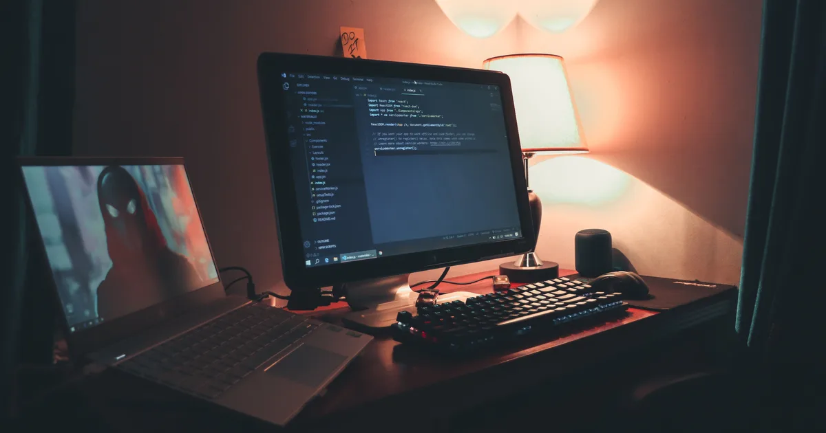 A dual-monitor developer workspace displaying code, empty of its occupant